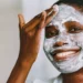 Black woman with facial skin bleaching damage using a clay mask to soothe and heal her skin
